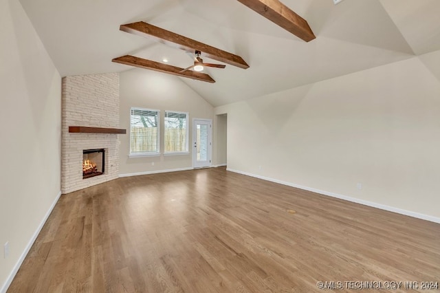 unfurnished living room featuring ceiling fan, hardwood / wood-style floors, vaulted ceiling with beams, and a fireplace