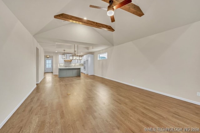 unfurnished living room featuring ceiling fan, lofted ceiling with beams, and light hardwood / wood-style flooring