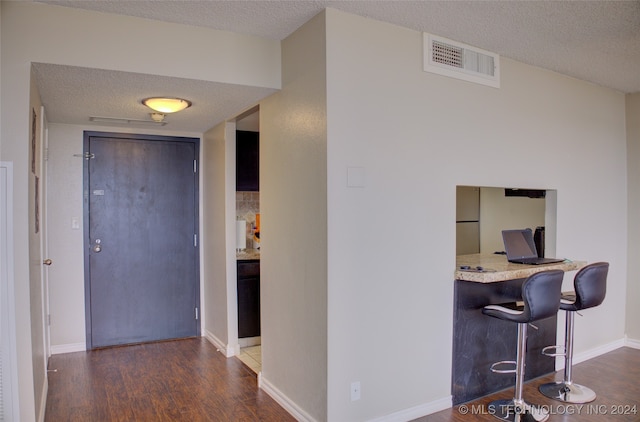 interior space with a textured ceiling, a breakfast bar, and dark hardwood / wood-style floors