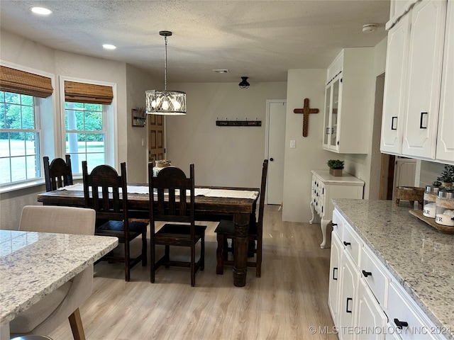 dining area featuring an inviting chandelier, a textured ceiling, and light hardwood / wood-style flooring