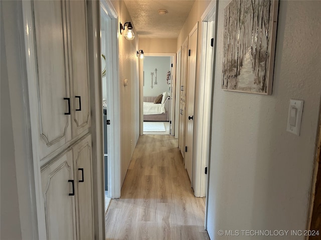 hall featuring light hardwood / wood-style floors and a textured ceiling