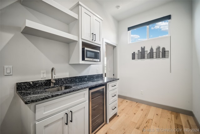 kitchen with dark stone counters, wine cooler, sink, and white cabinetry