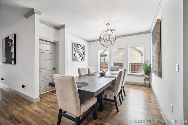 dining room with ornamental molding, an inviting chandelier, and dark hardwood / wood-style floors