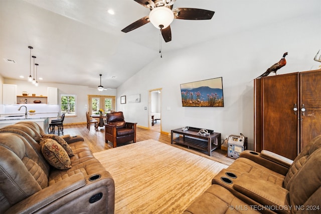 living room featuring light hardwood / wood-style flooring, ceiling fan, sink, and vaulted ceiling