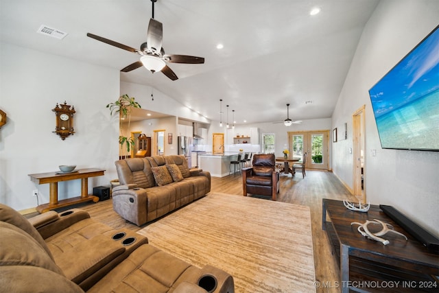 living room with light hardwood / wood-style flooring, ceiling fan, and vaulted ceiling