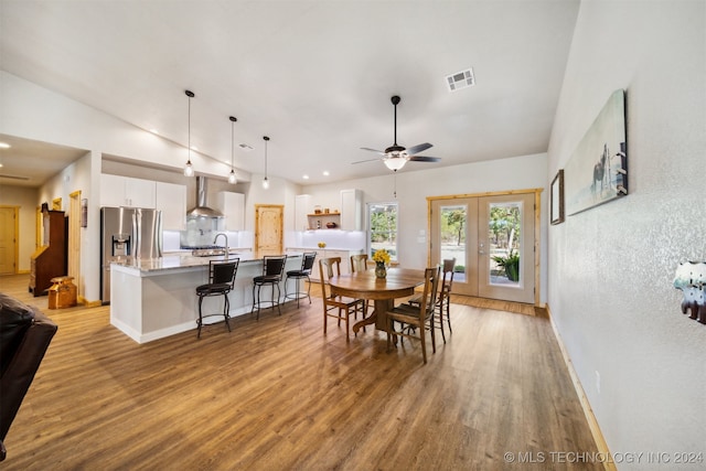 dining space with sink, ceiling fan, french doors, lofted ceiling, and light hardwood / wood-style floors