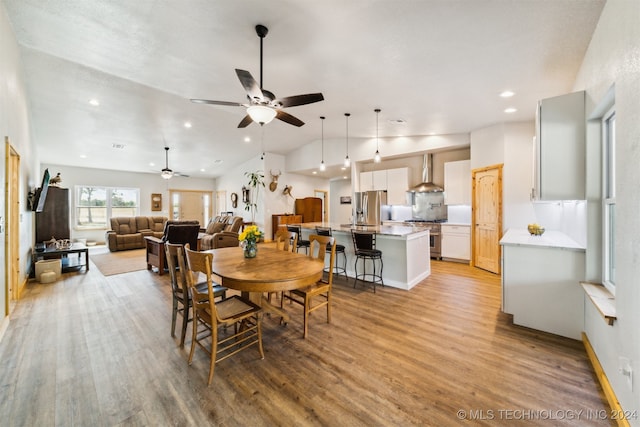 dining area featuring light wood-type flooring, vaulted ceiling, and ceiling fan