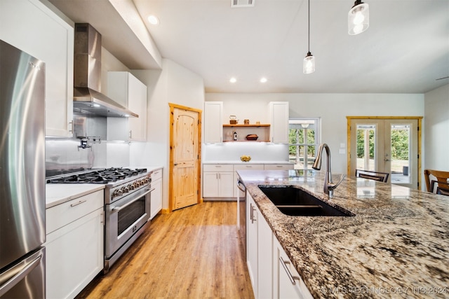 kitchen featuring white cabinetry, stainless steel appliances, sink, wall chimney exhaust hood, and light hardwood / wood-style floors