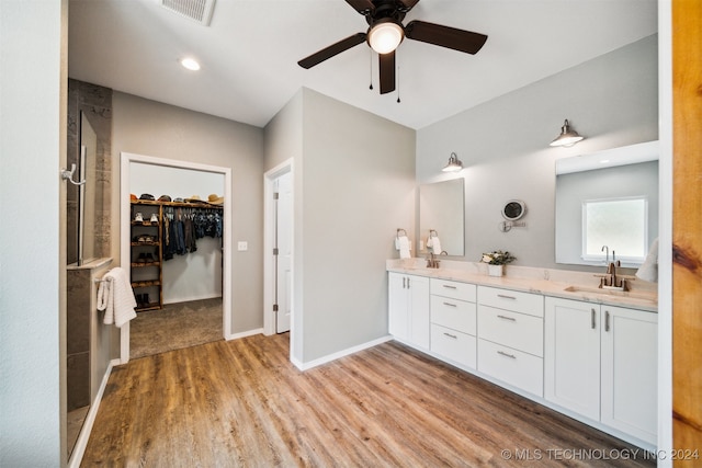 bathroom featuring ceiling fan, hardwood / wood-style flooring, a tile shower, and vanity