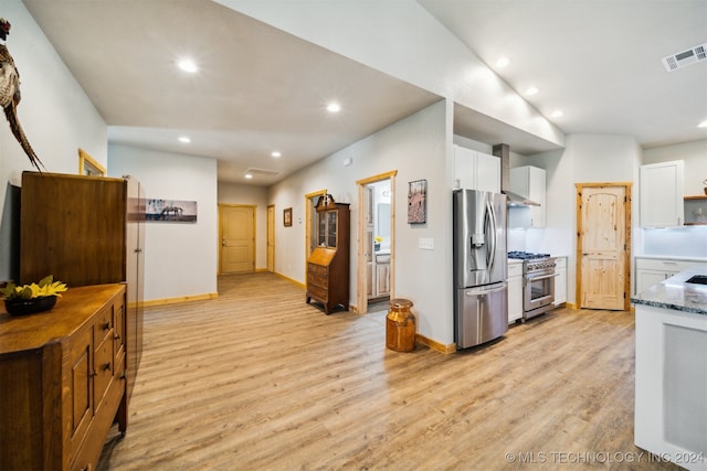 kitchen featuring light wood-type flooring, white cabinets, stainless steel appliances, and dark stone counters