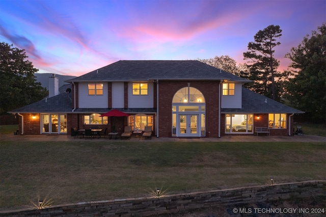 view of front facade featuring french doors, a yard, and a patio area