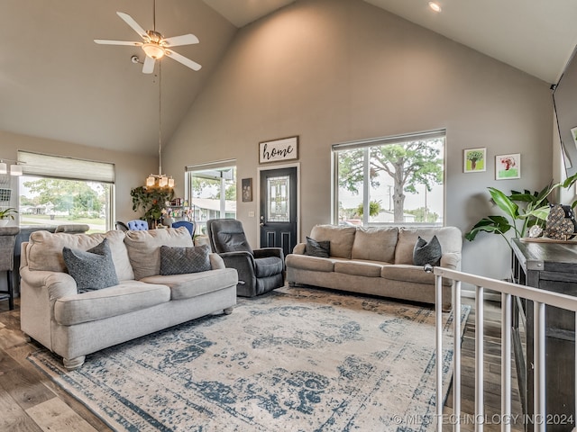 living room with high vaulted ceiling, wood-type flooring, and ceiling fan with notable chandelier