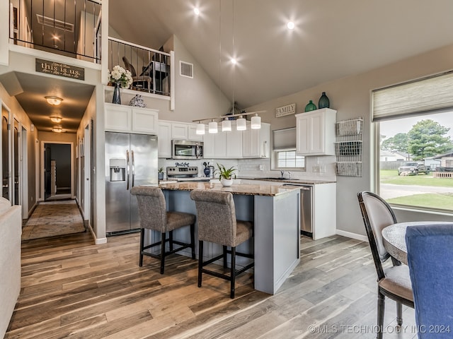 kitchen with white cabinetry, light hardwood / wood-style floors, appliances with stainless steel finishes, and a kitchen island