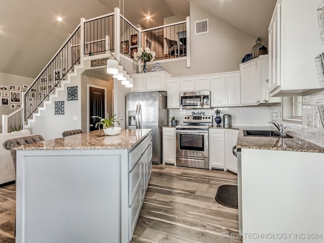 kitchen featuring decorative backsplash, light wood-type flooring, white cabinetry, appliances with stainless steel finishes, and high vaulted ceiling