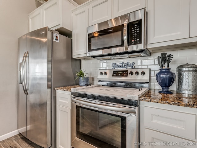 kitchen featuring appliances with stainless steel finishes, white cabinetry, and dark stone countertops