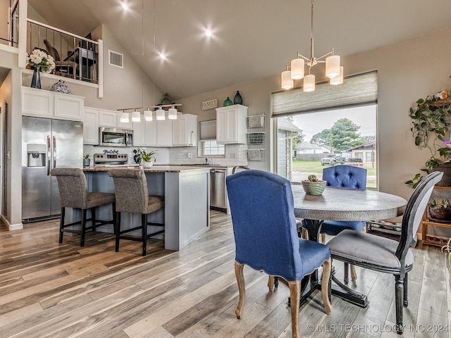 dining room with a notable chandelier, high vaulted ceiling, and light hardwood / wood-style flooring