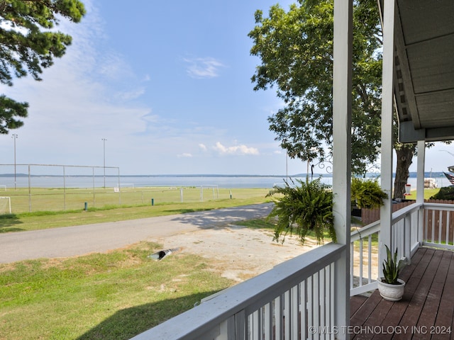 wooden terrace with a water view and a lawn