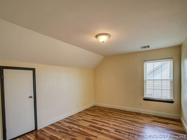 additional living space featuring lofted ceiling and wood-type flooring