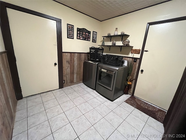 laundry room featuring washer and dryer, light tile patterned floors, and wooden walls