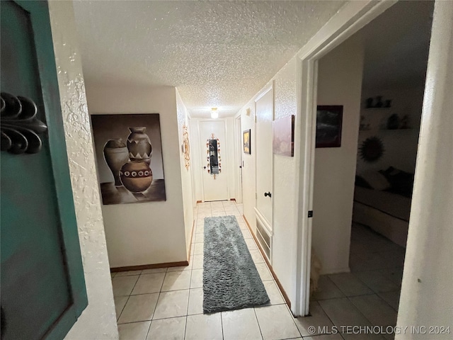 hall with light tile patterned flooring and a textured ceiling