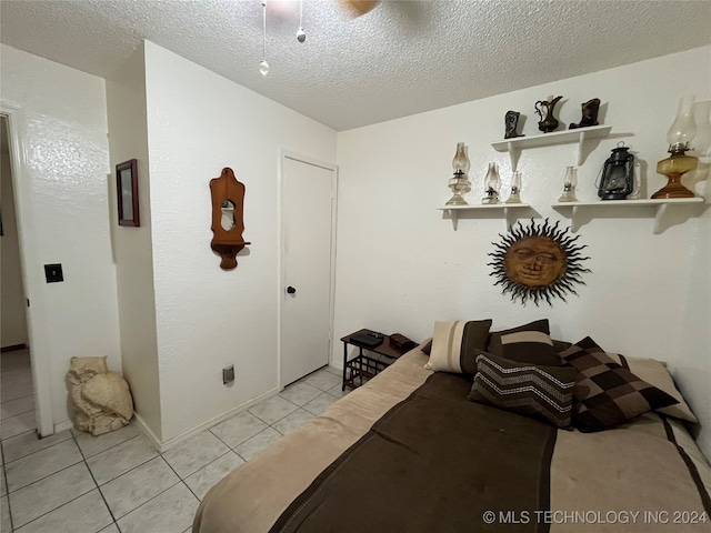 bedroom with a textured ceiling, light tile patterned floors, and ceiling fan