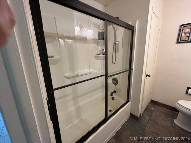 bathroom with toilet and bath / shower combo with glass door