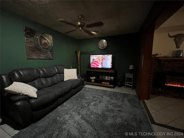 tiled living room featuring a fireplace, a textured ceiling, and ceiling fan