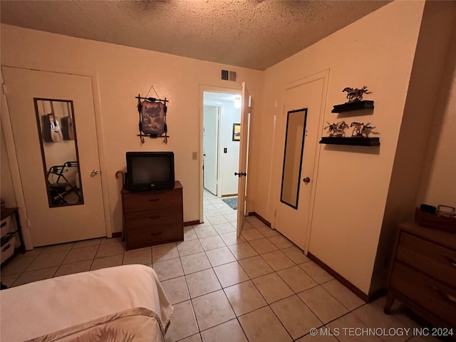 bedroom with a textured ceiling and light tile patterned flooring