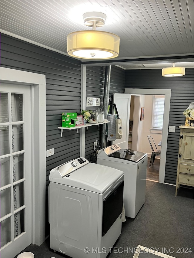 laundry area with washer and clothes dryer, dark colored carpet, and wooden walls