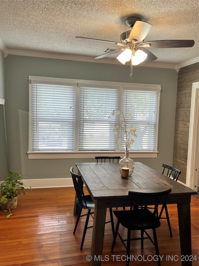 dining room featuring a textured ceiling, ceiling fan, ornamental molding, and wood-type flooring