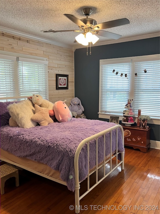 bedroom featuring multiple windows, ceiling fan, wood-type flooring, and a textured ceiling