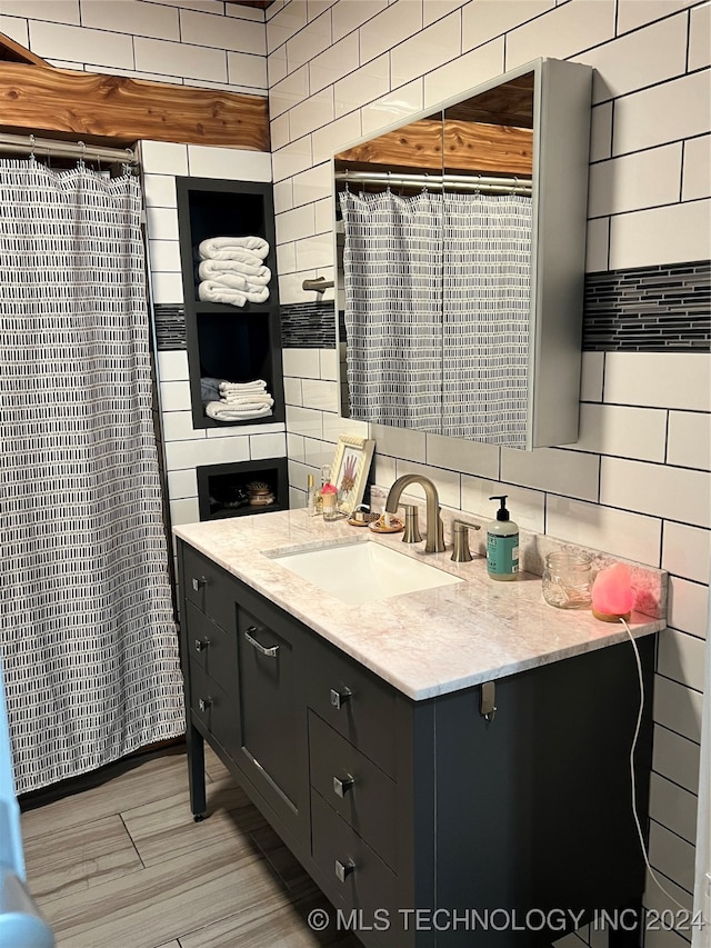 bathroom featuring vanity, tile walls, wood-type flooring, and decorative backsplash