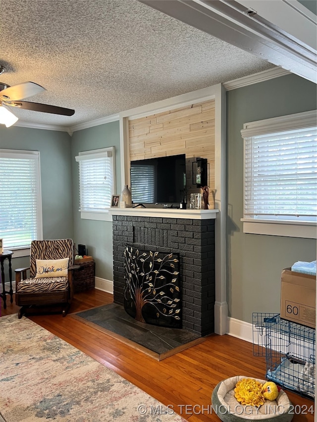 living room with a fireplace, a textured ceiling, wood-type flooring, and ceiling fan