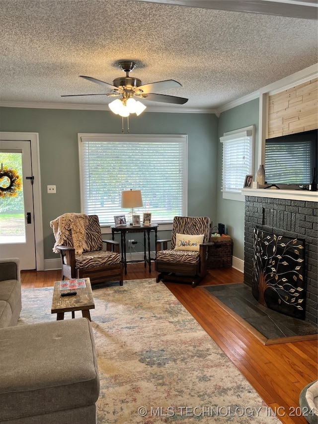 living room featuring a textured ceiling, a brick fireplace, hardwood / wood-style floors, and ceiling fan