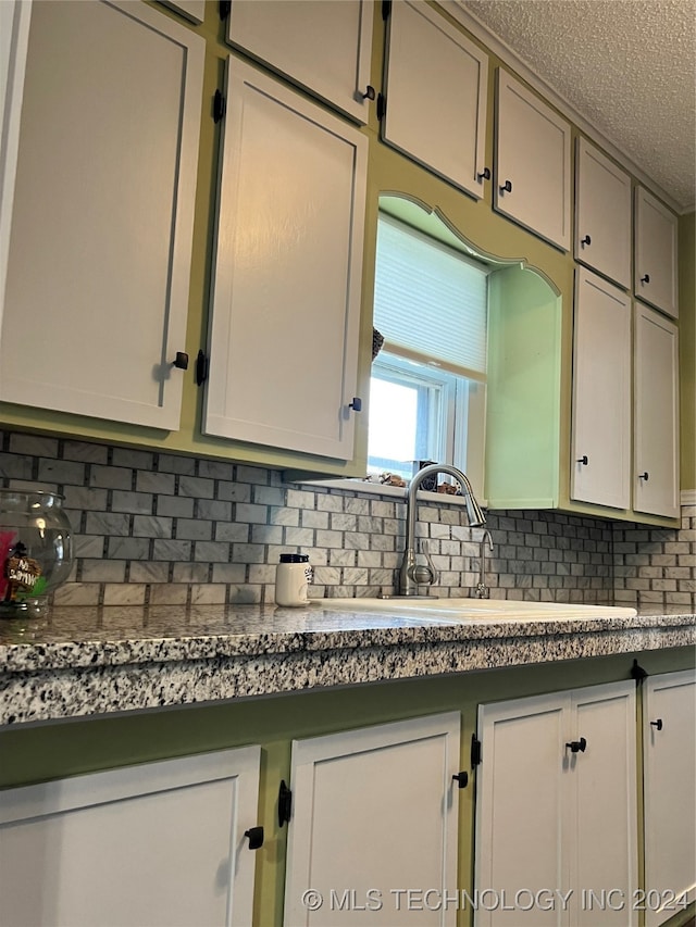 kitchen featuring a textured ceiling, sink, and decorative backsplash