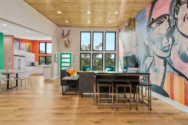 dining area featuring wood ceiling, a high ceiling, and light wood-type flooring