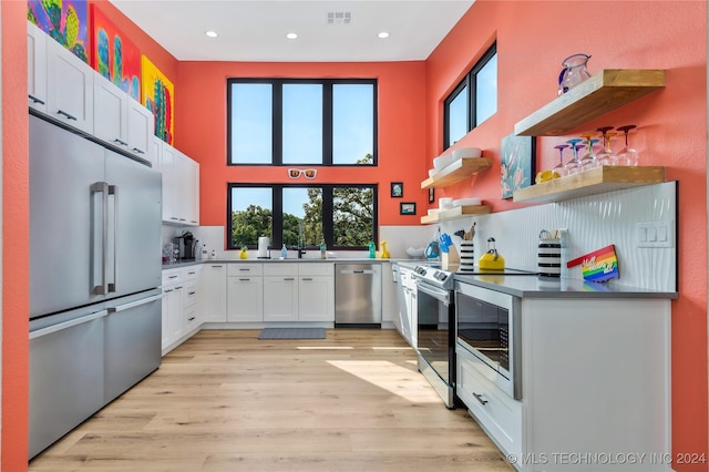 kitchen featuring stainless steel appliances, a wealth of natural light, white cabinets, and light hardwood / wood-style flooring