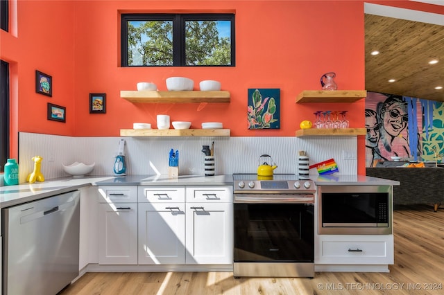 bar featuring appliances with stainless steel finishes, white cabinets, light hardwood / wood-style floors, and decorative backsplash