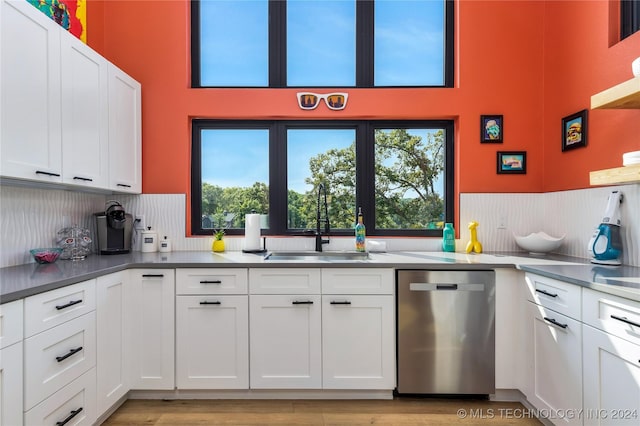 kitchen featuring white cabinetry, dishwasher, sink, backsplash, and light wood-type flooring