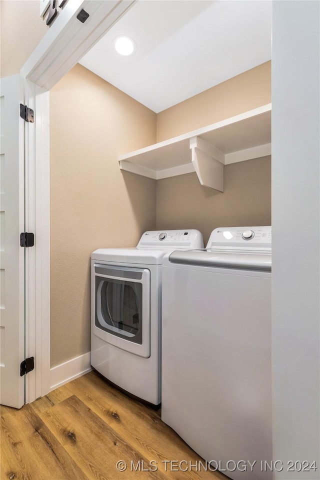 clothes washing area featuring washing machine and clothes dryer and light hardwood / wood-style floors