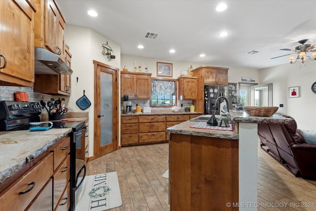 kitchen featuring black electric range, ceiling fan, an island with sink, and light hardwood / wood-style flooring