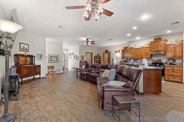 living area featuring visible vents, recessed lighting, light wood-type flooring, and a wood stove