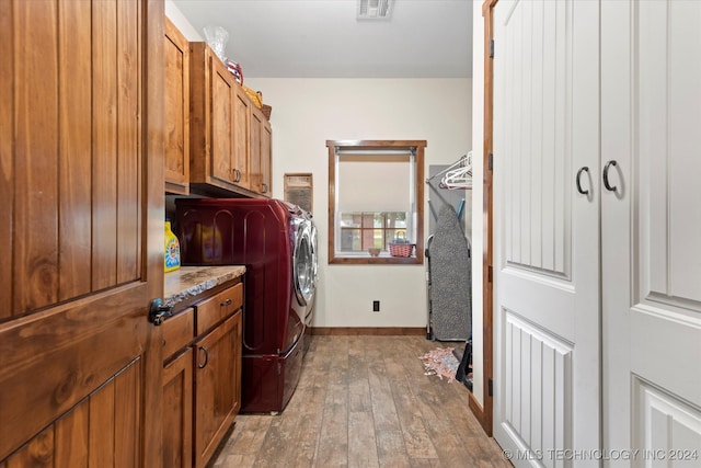 laundry room featuring wood-type flooring, independent washer and dryer, and cabinets