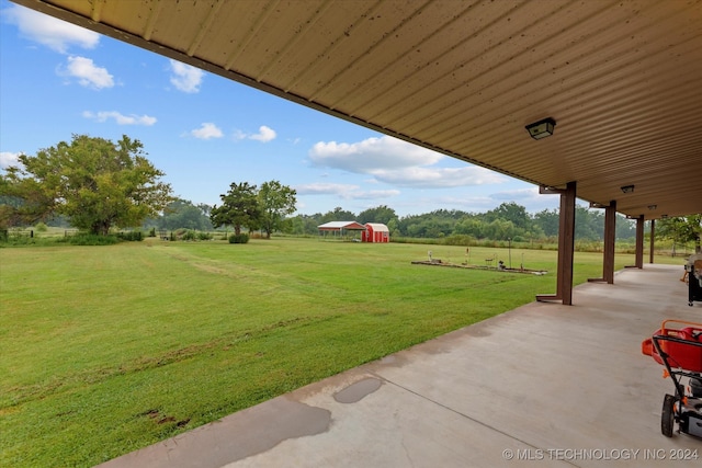 view of yard featuring a rural view, a storage unit, and a patio area