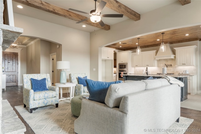 living room with ceiling fan, beam ceiling, and sink