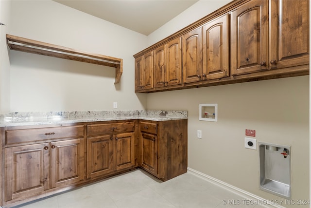 clothes washing area with hookup for a washing machine, electric dryer hookup, light tile patterned floors, and cabinets