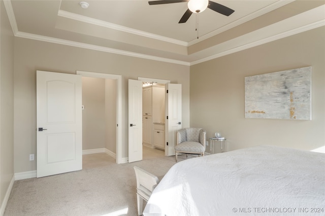 carpeted bedroom with crown molding, a raised ceiling, ceiling fan, and ensuite bath