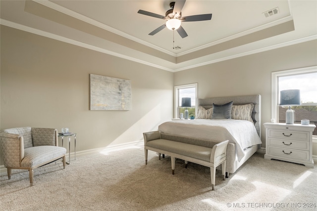 carpeted bedroom featuring a tray ceiling, crown molding, and ceiling fan