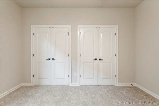 unfurnished bedroom with two closets and carpet floors