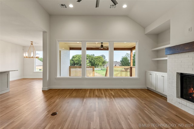 unfurnished living room featuring light hardwood / wood-style flooring, ceiling fan with notable chandelier, a wealth of natural light, and a brick fireplace